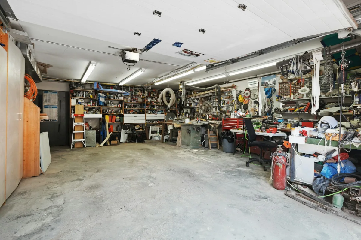 Domestic garage workshop with a bare poured concrete floor and benches along the wall